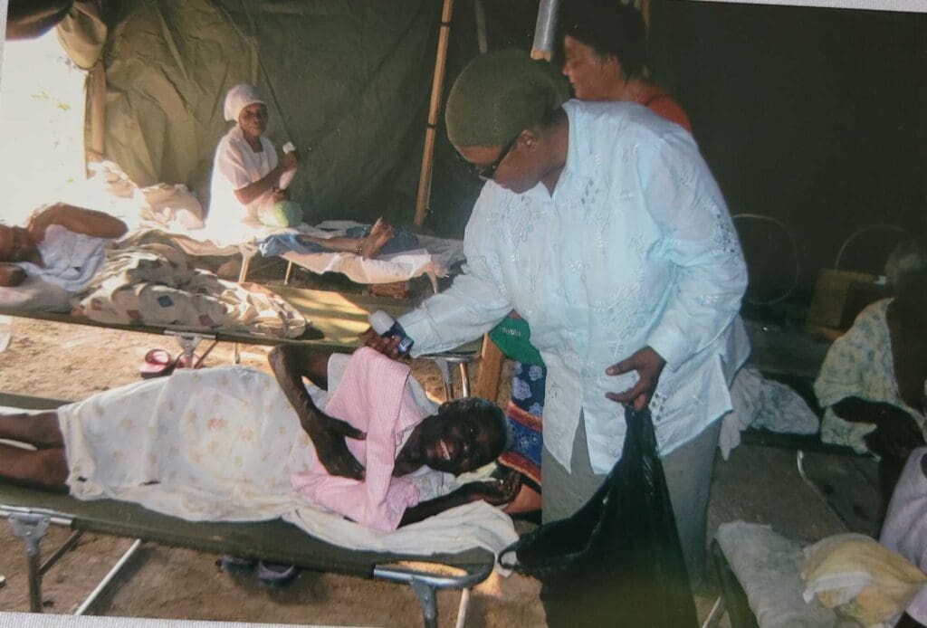 A man standing next to a woman in bed.