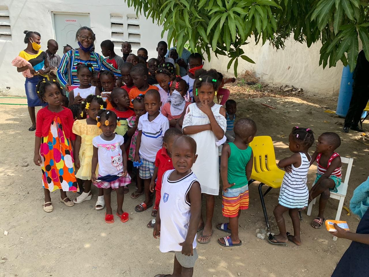 A group of children standing in front of a tree.