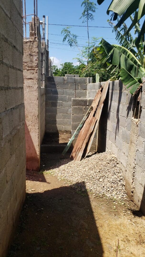 A dirt path leading to an unfinished building.