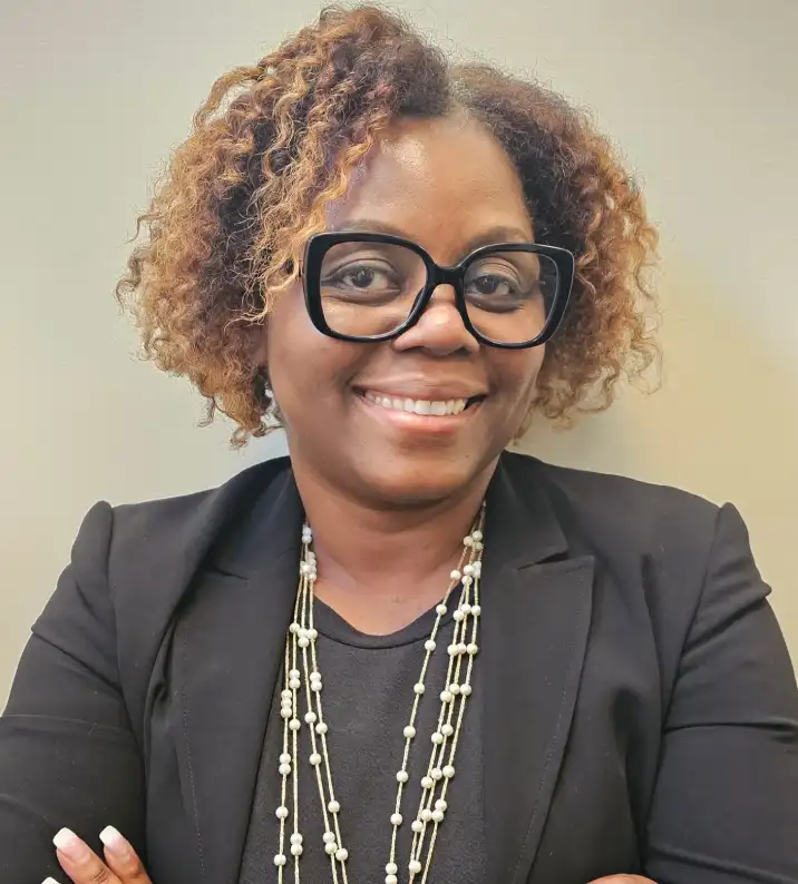 A woman with glasses and curly hair wearing a black jacket.