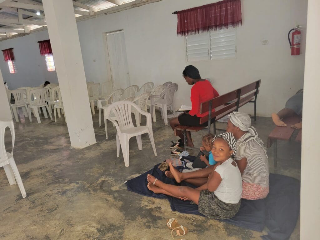 Three people sitting on a bench in an empty room.