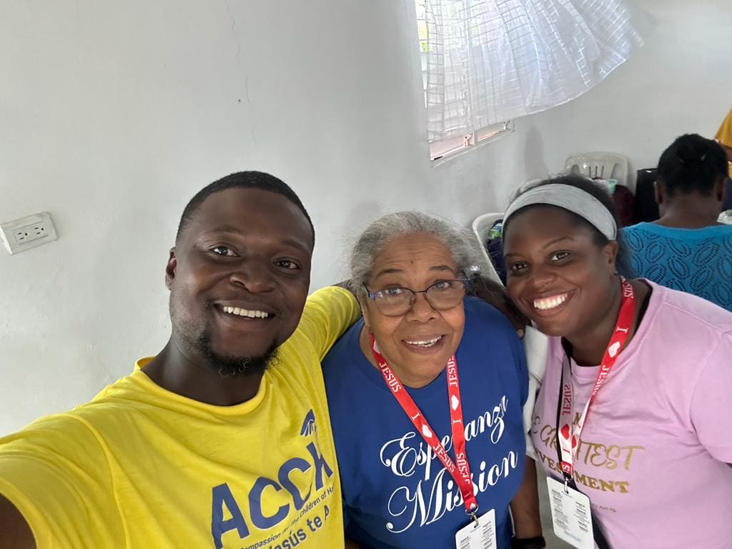 Three people smiling for a picture in front of a wall.