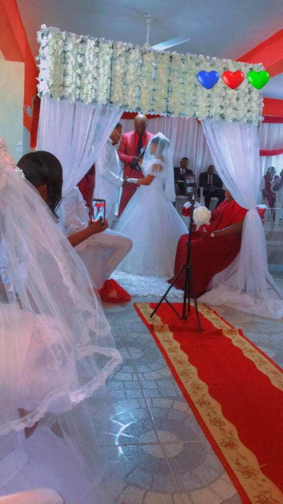 A bride and groom sitting in front of their wedding party.