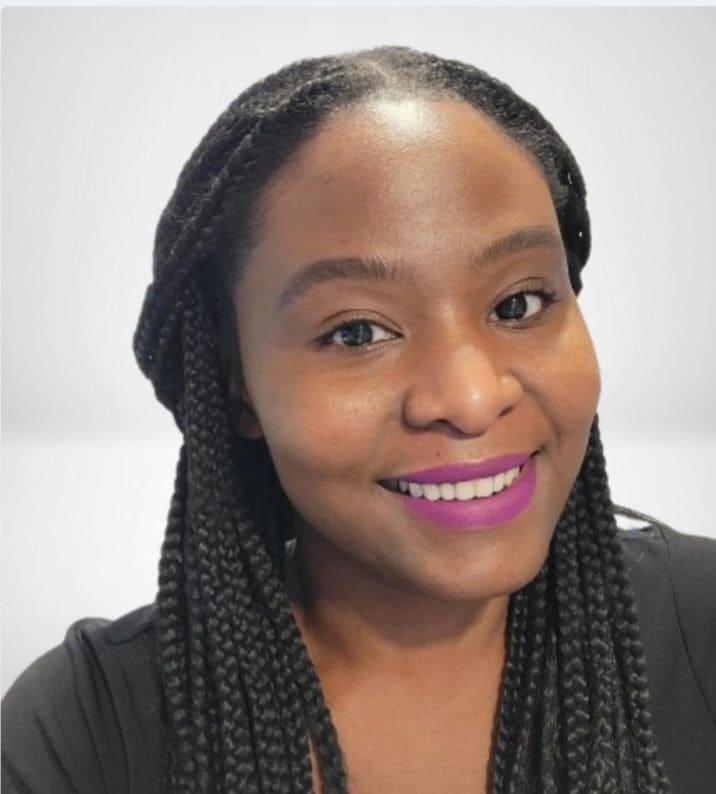 A woman with braids is smiling for the camera.